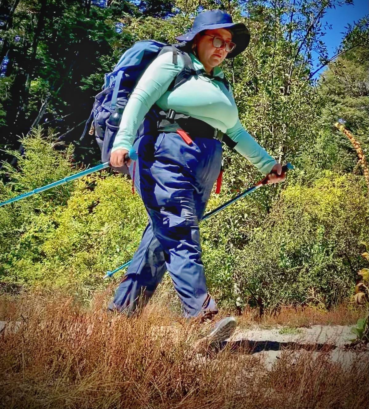 Fanzuri Gómez caminando con morral y bastones en la Patagonia